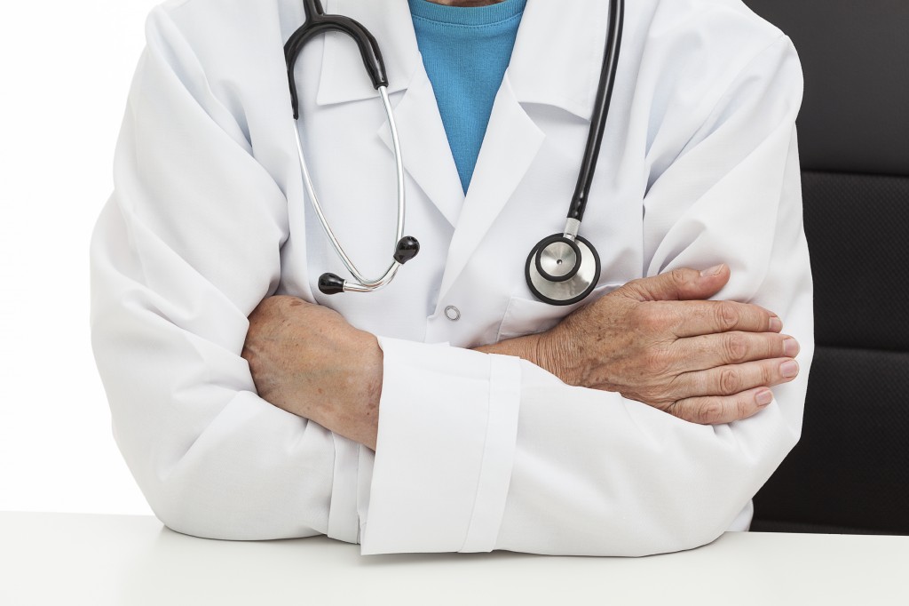 An old doctor sitting with his arms crossed