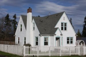 A cute little steep roofed home and fence